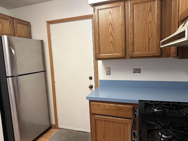 2S809 Grove Ln, Warrenville, IL 60555 - kitchen with freestanding refrigerator, brown cabinets, gas stove, light wood-style floors, and under cabinet range hood