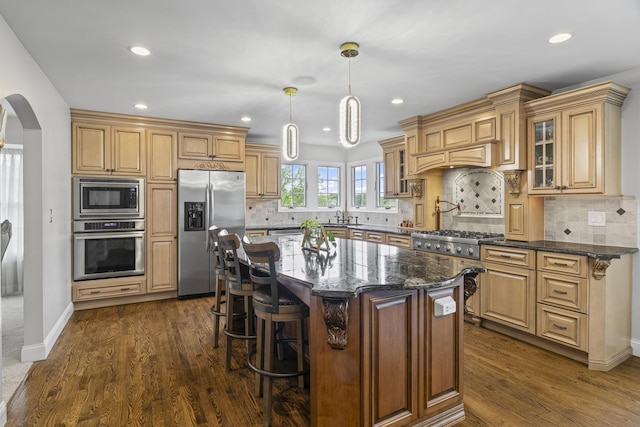 1086 Brighton Dr, Carol Stream, IL 60188 - kitchen featuring appliances with stainless steel finishes, arched walkways, glass insert cabinets, recessed lighting, and a breakfast bar area