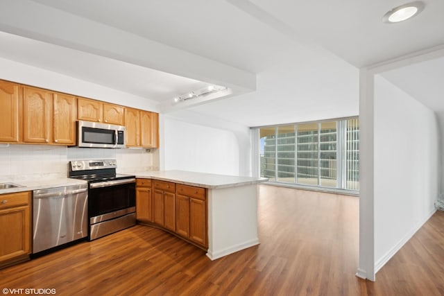 300 N State St Unit 3205, Chicago, IL 60654 - kitchen with appliances with stainless steel finishes, dark wood-type flooring, a peninsula, decorative backsplash, and light countertops