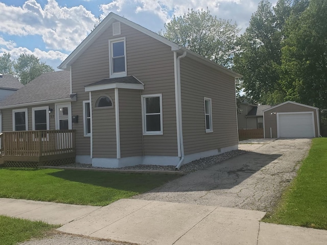 53 N Walnut St, Manteno, IL 60950 - view of front of house with an outdoor structure, asphalt driveway, a front lawn, a wooden deck, and a detached garage