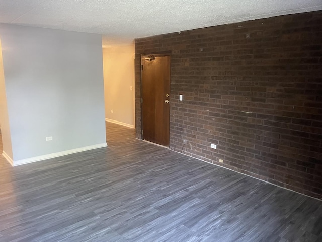 1616 Richmond Cir Unit 101, Joliet, IL 60435 - unfurnished room featuring brick wall, dark wood-style floors, baseboards, and a textured ceiling
