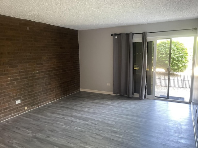 1616 Richmond Cir Unit 101, Joliet, IL 60435 - empty room with brick wall, wood finished floors, baseboards, and a textured ceiling