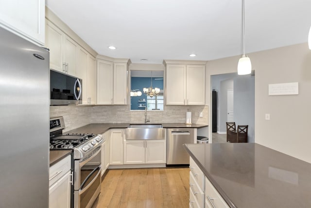 646 S Curran Rd, Round Lake, IL 60073 - kitchen featuring appliances with stainless steel finishes, a sink, dark countertops, backsplash, and a chandelier