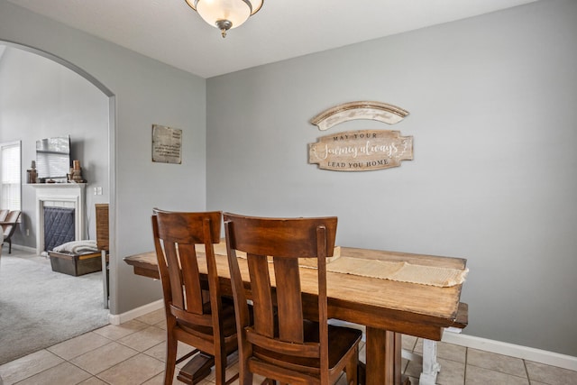 713 Sedgegrass Dr, Champaign, IL 61822 - dining room featuring arched walkways, light tile patterned floors, a fireplace, and light carpet