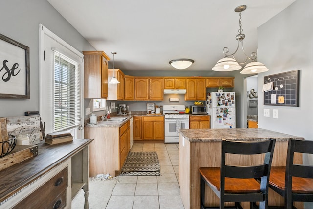 713 Sedgegrass Dr, Champaign, IL 61822 - kitchen featuring white appliances, under cabinet range hood, light tile patterned floors, hanging light fixtures, and a breakfast bar area