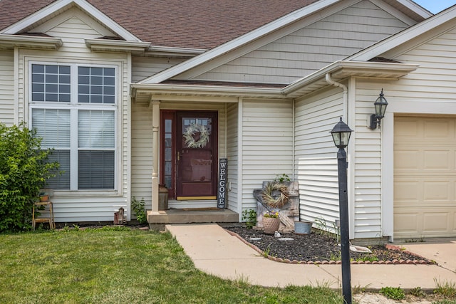 713 Sedgegrass Dr, Champaign, IL 61822 - view of exterior entry with a garage, a yard, and a shingled roof