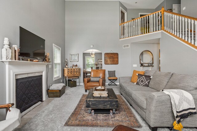 713 Sedgegrass Dr, Champaign, IL 61822 - living room with arched walkways, carpet floors, a towering ceiling, a fireplace with flush hearth, and stairway
