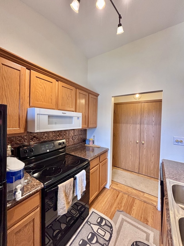 4316 W Shamrock Ln Unit 3C, Mchenry, IL 60050 - kitchen featuring black / electric stove, white microwave, backsplash, light wood-style floors, and brown cabinetry