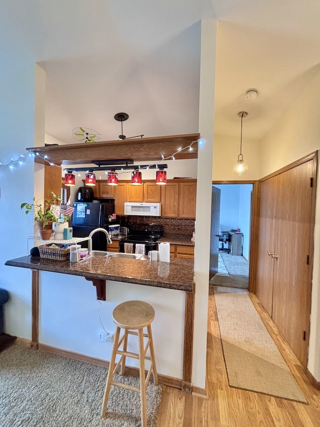4316 W Shamrock Ln Unit 3C, Mchenry, IL 60050 - kitchen with black appliances, a peninsula, brown cabinetry, backsplash, and a breakfast bar area