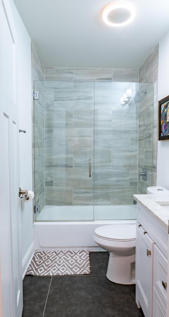 1009 Lathrop Ave, Forest Park, IL 60130 - full bathroom with vanity, shower / bath combination with glass door, toilet, and tile patterned floors