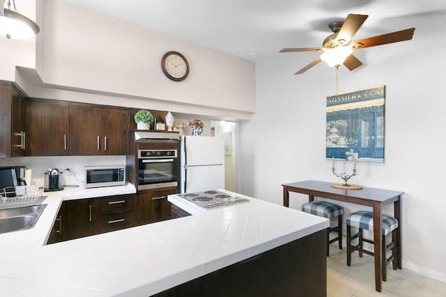 96 E Quincy St, Riverside, IL 60546 - kitchen with appliances with stainless steel finishes, dark brown cabinetry, ceiling fan, tile counters, and baseboards
