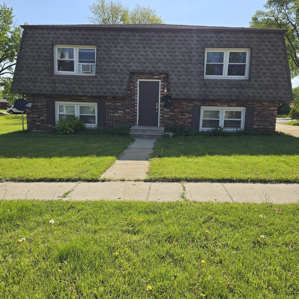 126 Sabin St, Sycamore, IL 60178 - view of front facade with a shingled roof, brick siding, a front lawn, and mansard roof