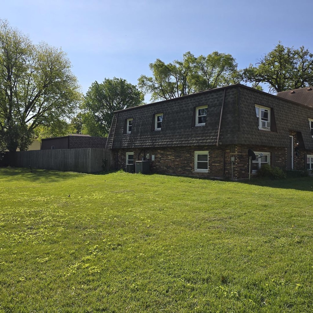 126 Sabin St, Sycamore, IL 60178 - back of property featuring mansard roof, central AC, brick siding, and roof with shingles