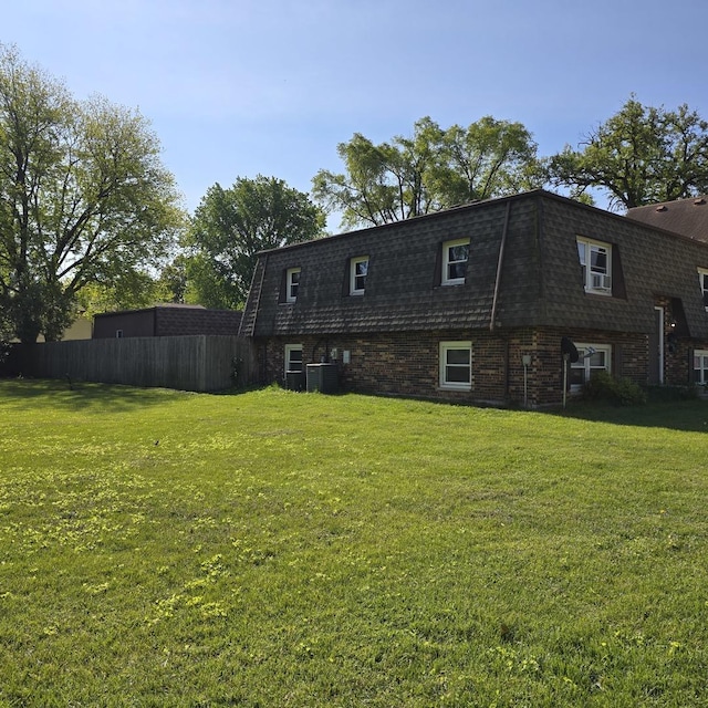 126 Sabin St, Sycamore, IL 60178 - back of property featuring mansard roof, central AC, brick siding, and roof with shingles