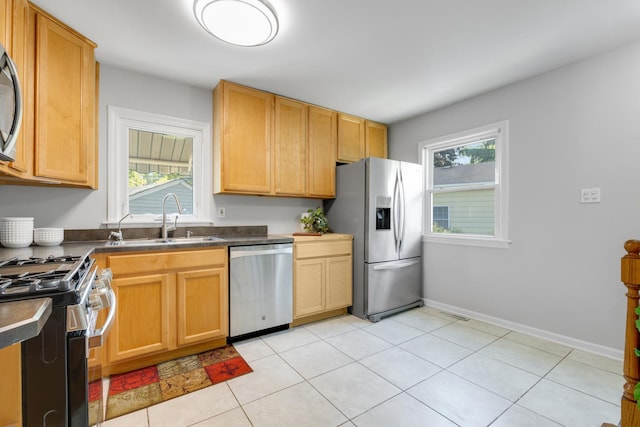 124 N W End Ave, Westmont, IL 60559 - kitchen featuring appliances with stainless steel finishes, a sink, dark countertops, light tile patterned flooring, and baseboards