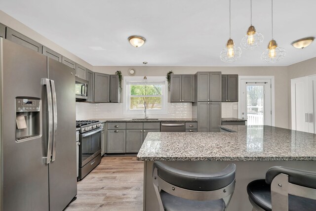 710 Sunset Ln, Shorewood, IL 60404 - kitchen featuring stainless steel appliances, gray cabinetry, a kitchen breakfast bar, and light stone counters