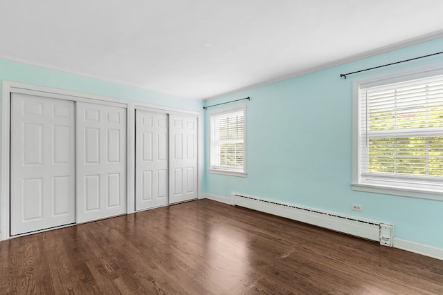 1412 Hinman Ave Unit 2W, Evanston, IL 60201 - unfurnished bedroom with a baseboard heating unit, two closets, multiple windows, and wood finished floors