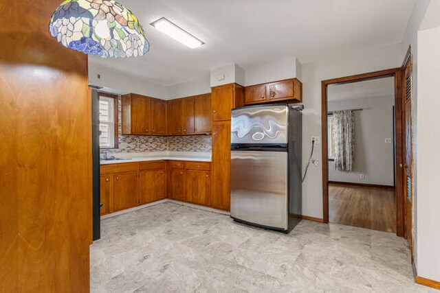 307 N Carico St, Tuscola, IL 61953 - kitchen featuring freestanding refrigerator, brown cabinets, light countertops, and tasteful backsplash