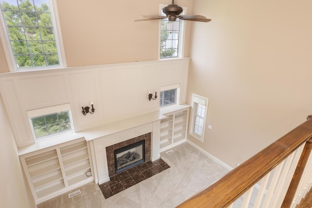 2004 Withers Ln, Bloomington, IL 61704 - unfurnished living room with a high end fireplace, ceiling fan, a decorative wall, and wainscoting