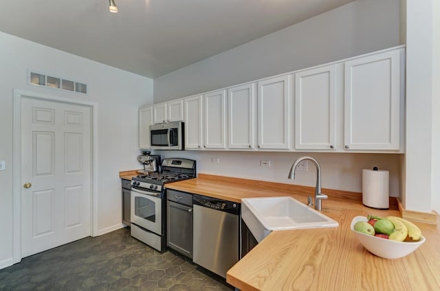 1924 Golden Gate Ln, Naperville, IL 60563 - kitchen featuring appliances with stainless steel finishes, wooden counters, a sink, and white cabinetry