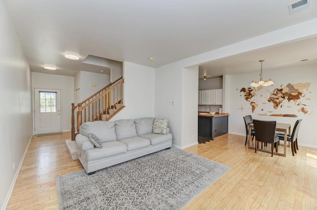 1924 Golden Gate Ln, Naperville, IL 60563 - living room featuring light wood-style floors, a chandelier, baseboards, and stairs