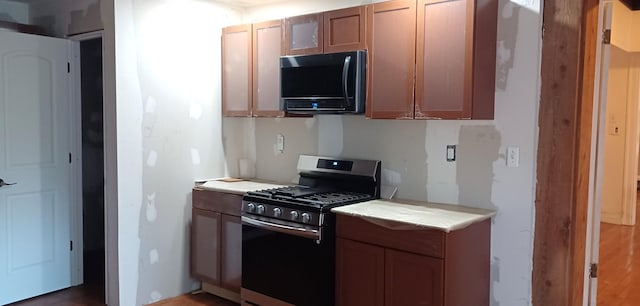 809 S Lynn St, Champaign, IL 61820 - kitchen featuring stainless steel gas range oven, black microwave, light countertops, and brown cabinetry