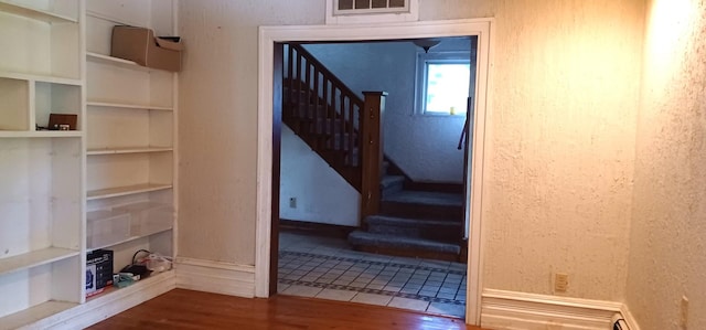 809 S Lynn St, Champaign, IL 61820 - stairway featuring wood finished floors, built in features, and a baseboard heating unit