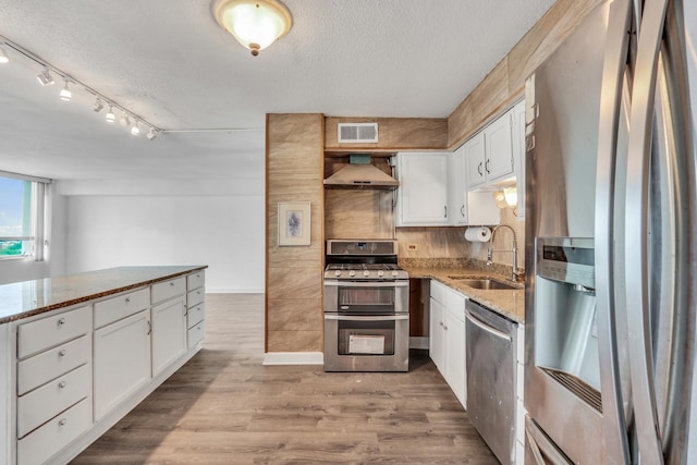 8801 W Golf Rd Unit 10C, Niles, IL 60714 - kitchen with stainless steel appliances, a sink, white cabinets, wall chimney exhaust hood, and a textured ceiling