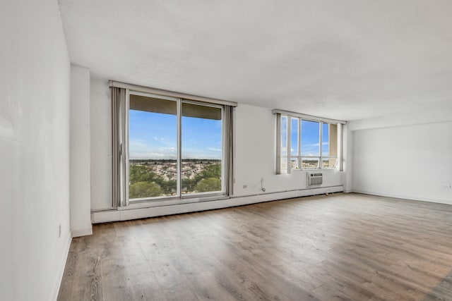8801 W Golf Rd Unit 10C, Niles, IL 60714 - empty room featuring wood finished floors, an AC wall unit, a baseboard heating unit, and baseboards