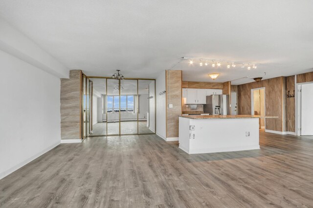 8801 W Golf Rd Unit 10C, Niles, IL 60714 - unfurnished living room featuring rail lighting, wood finished floors, baseboards, and wooden walls