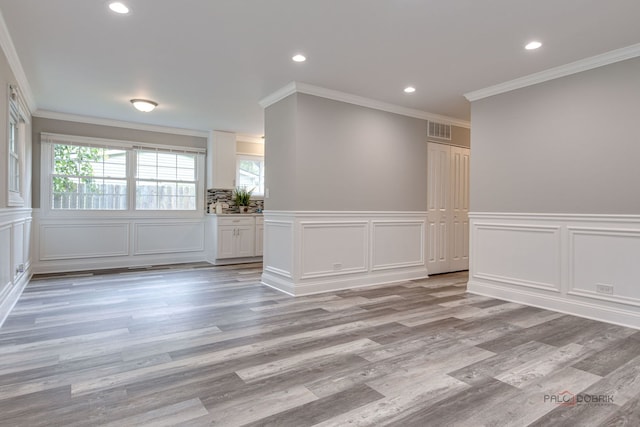 36586 N Traer Ter, Gurnee, IL 60031 - empty room with a decorative wall, crown molding, recessed lighting, wainscoting, and light wood finished floors
