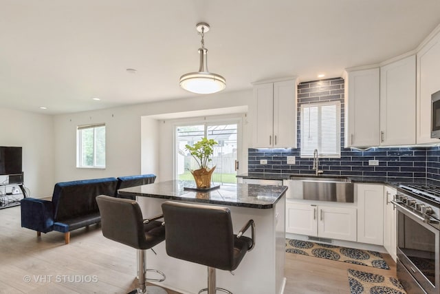 1714 Daybreak Ln, Zion, IL 60099 - kitchen featuring gas stove, a sink, light wood-type flooring, a breakfast bar, and a kitchen island