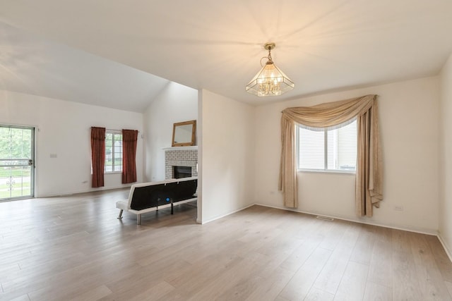1714 Daybreak Ln, Zion, IL 60099 - unfurnished living room featuring plenty of natural light, light wood-style floors, a chandelier, a brick fireplace, and lofted ceiling