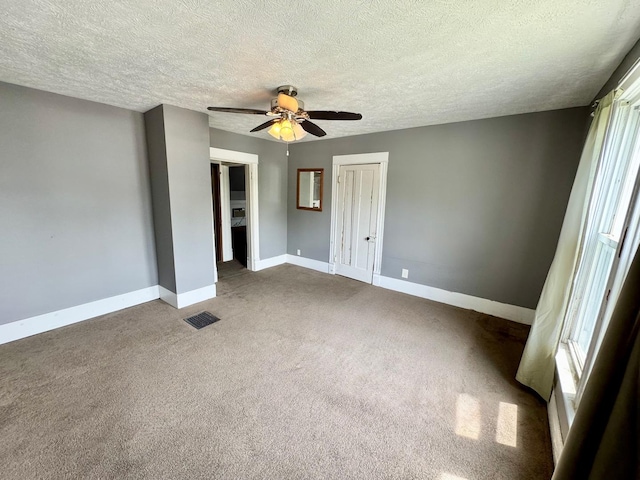 1303 W Locust St, Bloomington, IL 61701 - carpeted spare room with ceiling fan, baseboards, a textured ceiling, and healthy amount of natural light
