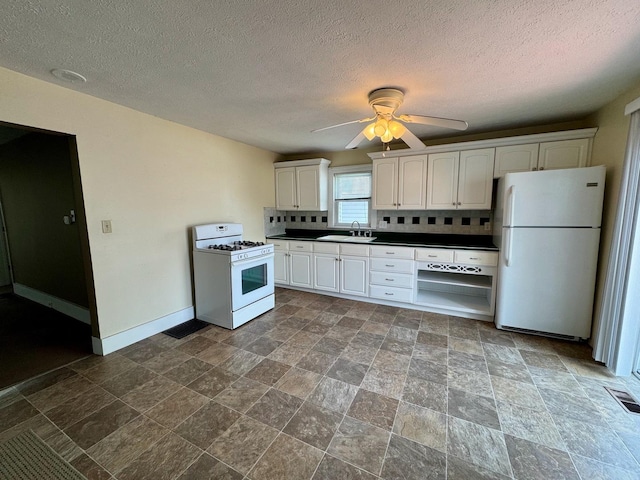 1303 W Locust St, Bloomington, IL 61701 - kitchen with white appliances, a sink, baseboards, dark countertops, and white cabinets