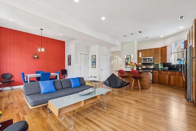 612 W Barry Ave Unit 3, Chicago, IL 60657 - living room featuring wallpapered walls, an accent wall, light wood-style floors, recessed lighting, and baseboards