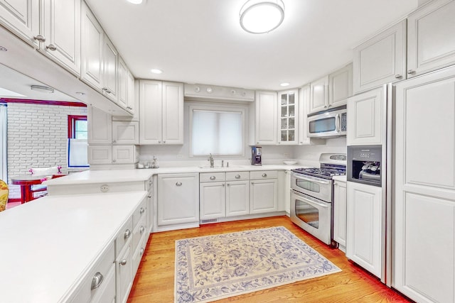 140 N Quincy St, Hinsdale, IL 60521 - kitchen featuring appliances with stainless steel finishes, light wood finished floors, light countertops, white cabinets, and a sink