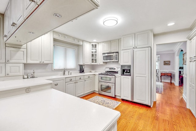 140 N Quincy St, Hinsdale, IL 60521 - kitchen featuring stainless steel appliances, light wood-style flooring, ornamental molding, white cabinets, and arched walkways