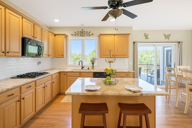 7N310 Ridge Line Rd, Saint Charles, IL 60175 - kitchen with black microwave, a sink, a breakfast bar, light wood-style floors, and decorative backsplash