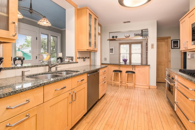 740 Wisner St, Park Ridge, IL 60068 - kitchen featuring appliances with stainless steel finishes, a sink, light wood-style floors, dark stone counters, and decorative backsplash
