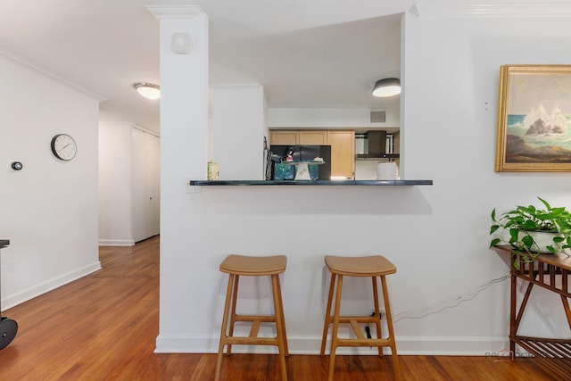 201 E Chestnut St Unit 3C, Chicago, IL 60611 - kitchen featuring a kitchen bar, wood finished floors, and baseboards