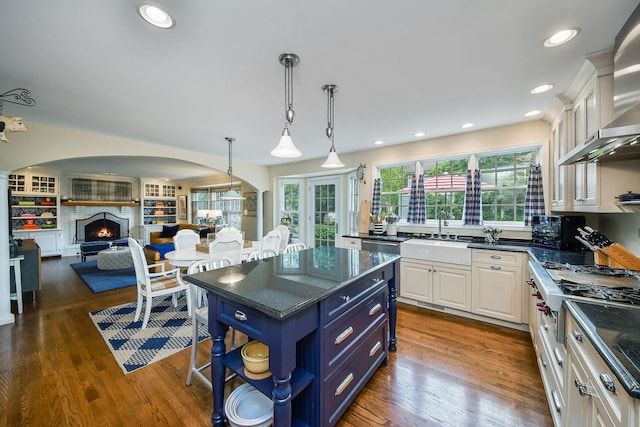 5234 Cedar Ct, Lisle, IL 60532 - kitchen featuring wall chimney range hood, white cabinetry, a sink, arched walkways, and stainless steel gas cooktop