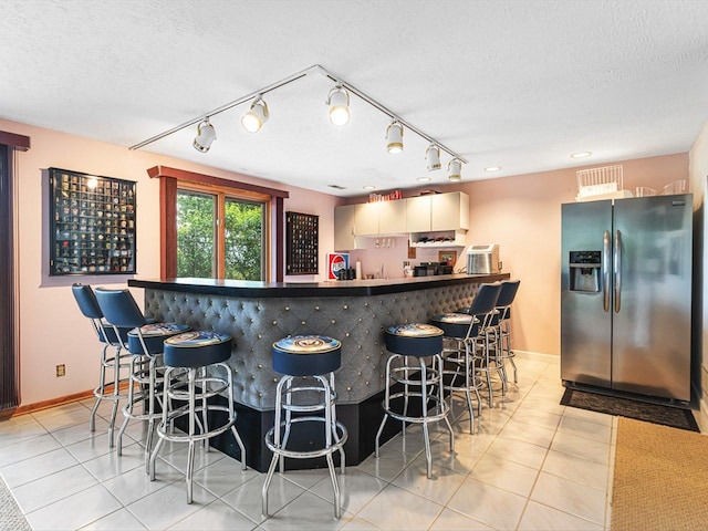 9104 E Weber Rd, Ridott, IL 61067 - indoor dry bar featuring stainless steel fridge with ice dispenser, light tile patterned floors, track lighting, and a textured ceiling