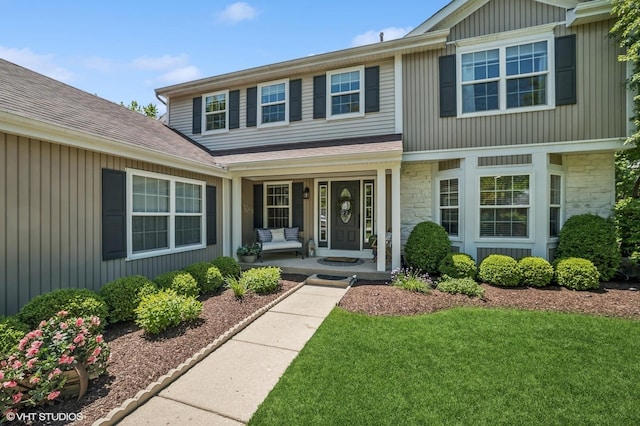 1250 Fernleaf Dr, Crystal Lake, IL 60014 - view of exterior entry featuring covered porch, stone siding, a lawn, and roof with shingles