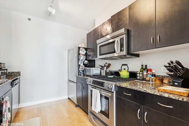 8 E Randolph St Unit 2407, Chicago, IL 60601 - kitchen featuring appliances with stainless steel finishes, dark stone counters, light wood-type flooring, and dark brown cabinets