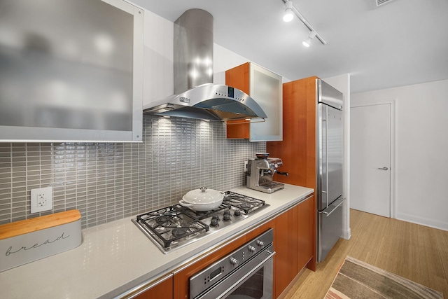 340 E Randolph St Unit 1304, Chicago, IL 60601 - kitchen featuring wall chimney exhaust hood, appliances with stainless steel finishes, light wood-type flooring, light countertops, and brown cabinets