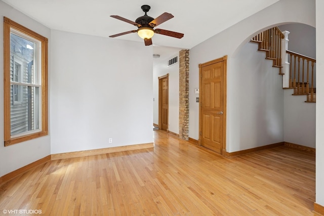 4308 N Whipple St, Chicago, IL 60618 - empty room with light wood-type flooring, arched walkways, ceiling fan, stairs, and baseboards