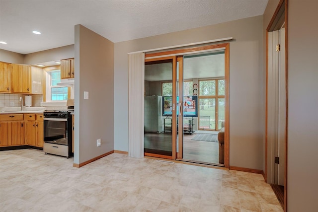 20541 E 2050 N Rd, Towanda, IL 61776 - kitchen with stainless steel range with gas cooktop, a sink, under cabinet range hood, baseboards, and light countertops
