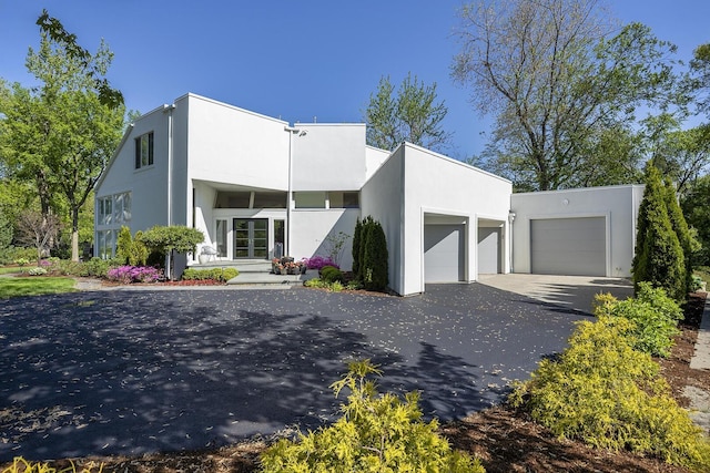 870 Woodbine Rd, Highland Park, IL 60035 - view of front facade with a garage, asphalt driveway, and stucco siding