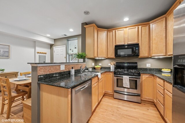 7315 N Honore St Unit 1, Chicago, IL 60626 - kitchen featuring stainless steel appliances, a peninsula, light wood-type flooring, a sink, and dark stone countertops